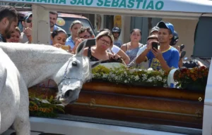 Cavalo em um funeral, cercado por pessoas em luto